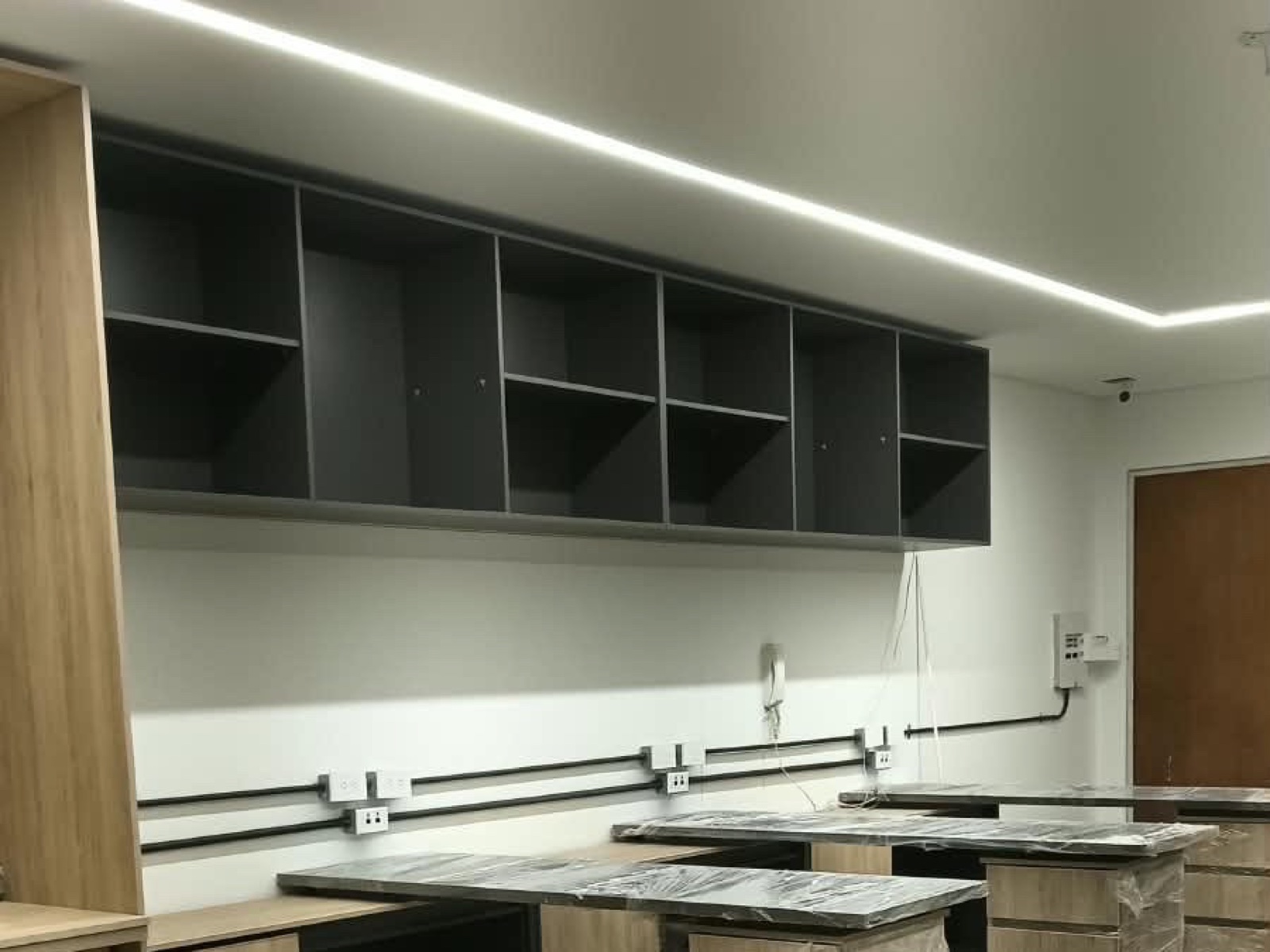 Oficina terminada con iluminación lineal LED y tomas sobre los puestos