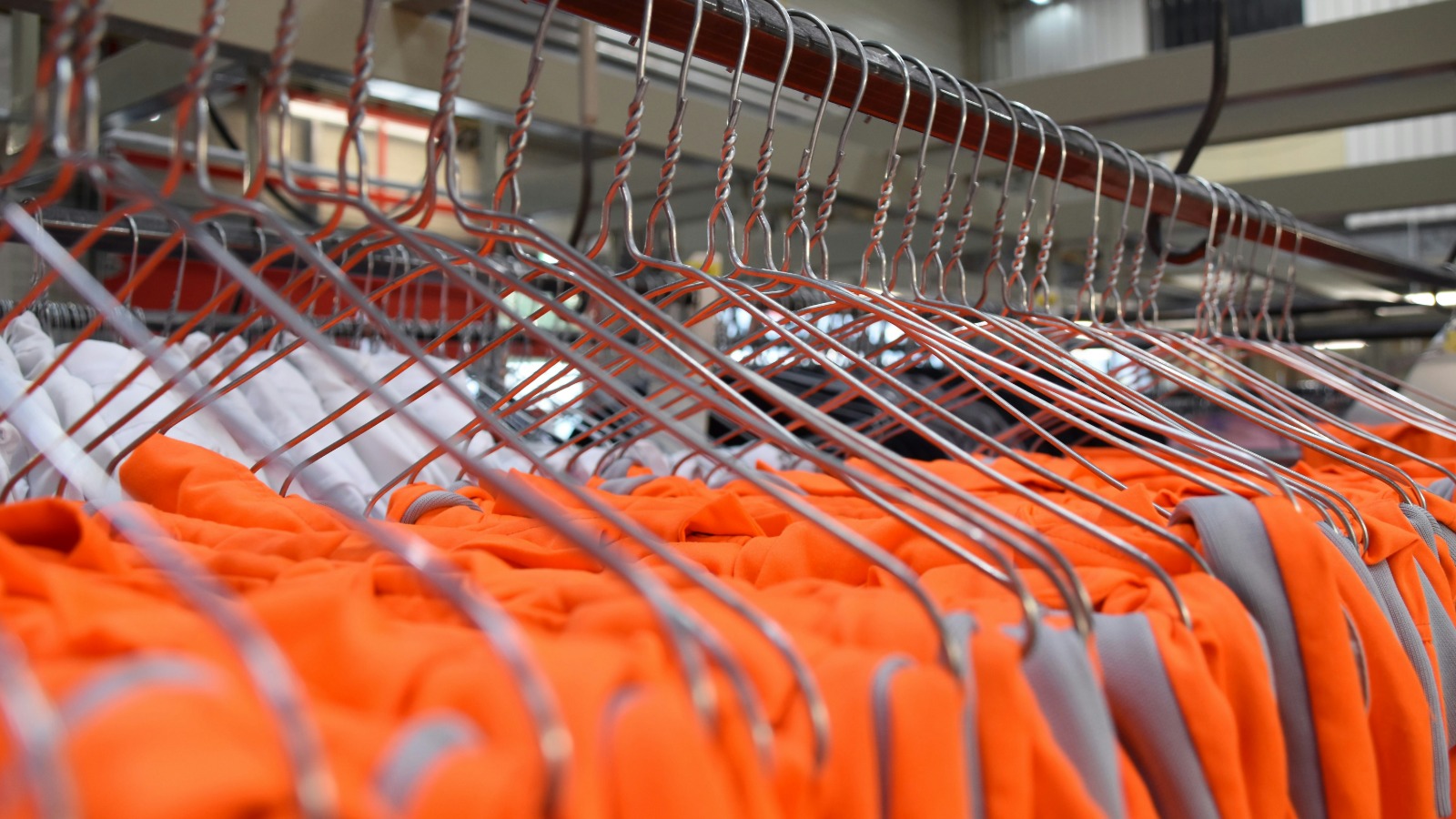 Prendas de trabajo naranjas organizadas en perchas
