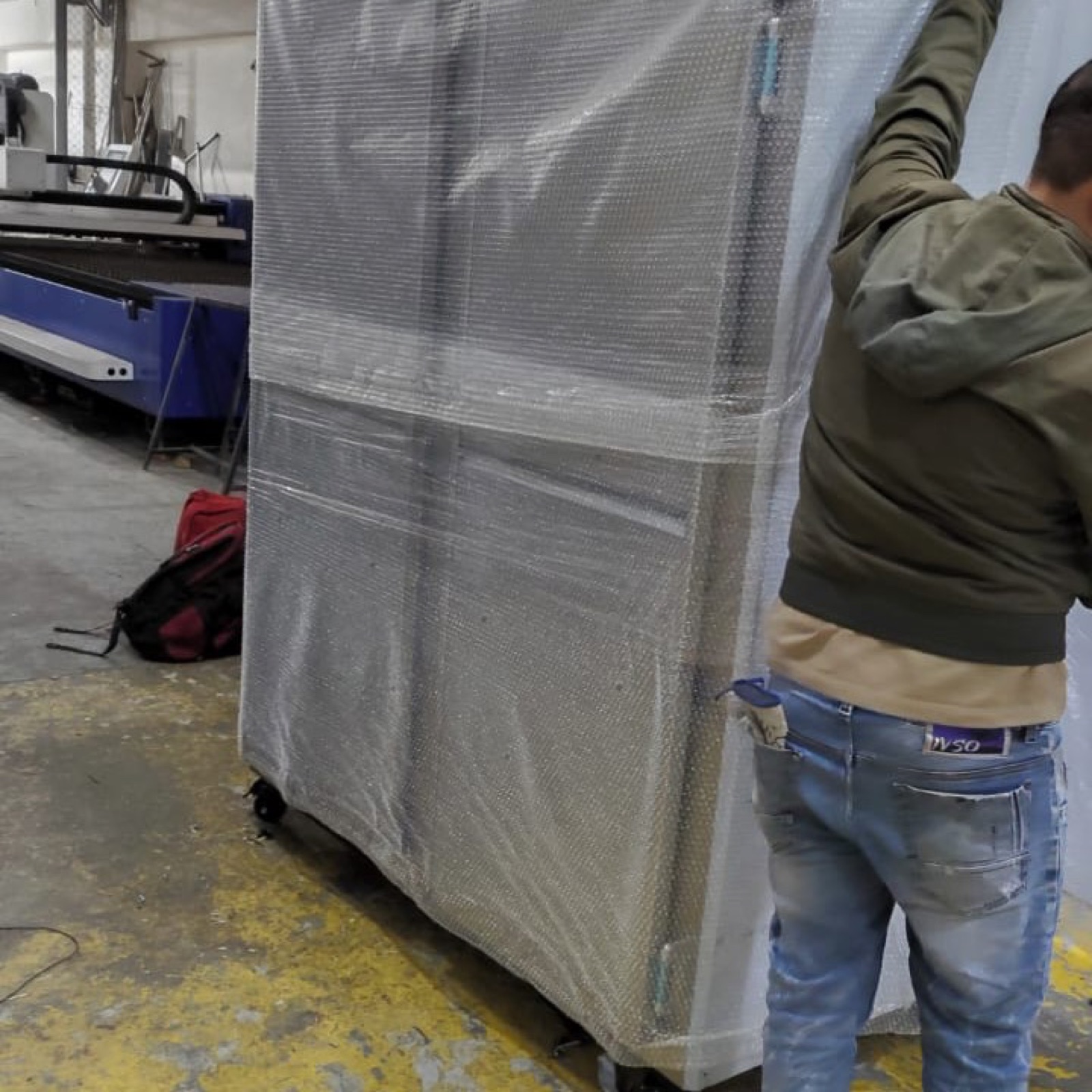 Técnico preparando la entrega de una nevera industrial de acero protegida con plástico